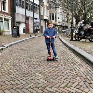 Jongen op een step over een straat met klinkers
