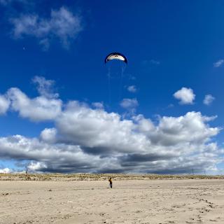 man vliegert op een groot strand