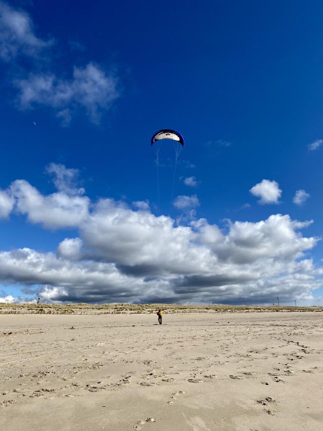 man vliegert op een groot strand