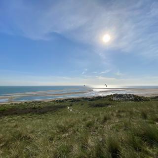 duinen en strand met in de verte een ondergaande zon boven de zee
