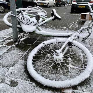 fiets ligt op straat, bedekt door een laagje sneeuw