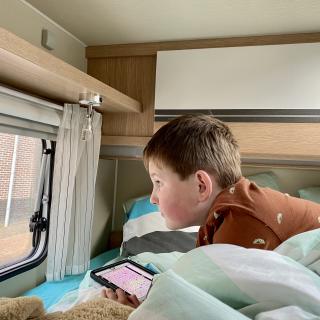 jongen kijkt door een raam van de camper naar buiten