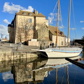 een zeilboot in de haven van Honfleur, onder een strak blauwe lucht