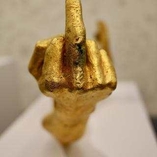 beeld van een gouden hand met opgestoken middelvinger