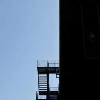 Donkere gebouw met open trappen tegen een blauwe lucht.