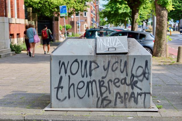 Graffiti op een afvalcontainer in een straat.